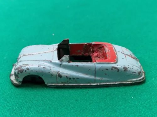 Vintage diecast toy car body, light blue with rusted red interior and damaged panel