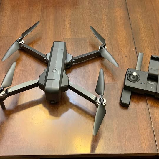 Foldable quadcopter drone with four propellers and central camera module.