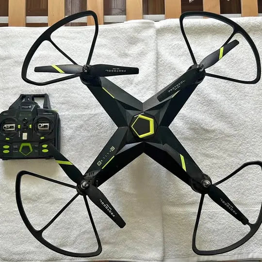 Stealth drone with camera, black body and neon yellow accents, four propellers, seen with controller