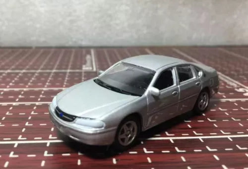Silver diecast sedan model car, front three-quarter view, 1:64 scale.