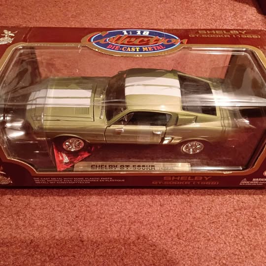 Die-cast metal car model, gold with black hood stripes, in clear display box