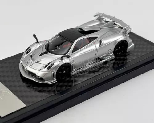 Silver 1:64 scale sports racing diecast car with black windows, on display base