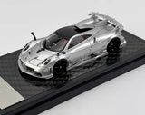 Silver 1:64 scale sports racing diecast car with black windows, on display base