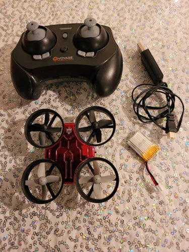 Palm-sized mini drone with black controller, four rotors, and charging cables