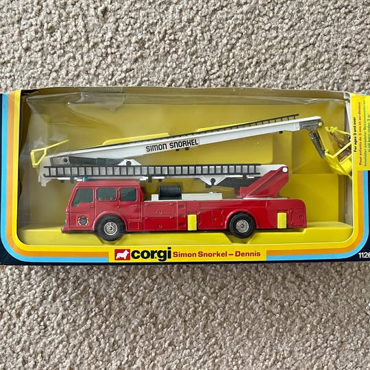 Red diecast fire engine toy with extended snorkel ladder, boxed