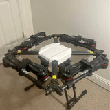 Agricultural spraying drone with radar, dark arms and white central body.