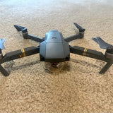 Gray foldable drone with four propellers and center camera housing