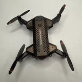 Black quadcopter drone with four propellers, camera-facing front body