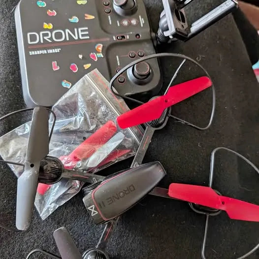Drone with controller, gray body and red prop guards, four rotors visible