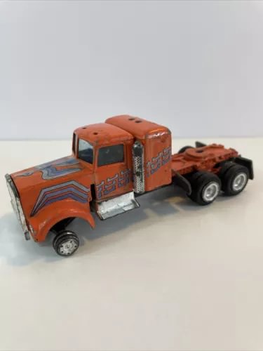 Vintage diecast semi truck cab, orange with decals and chrome details, on three axles