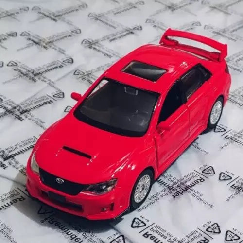 Red diecast model car toy with black windows and hood scoop, front 3/4 view