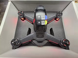 DJI FPV drone with four arms and propellers, gray body, red LED lights