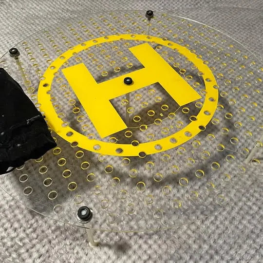 Yellow circular drone landing pad with H grip pattern and metal grommets