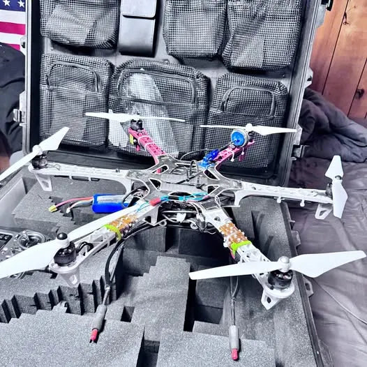 Quadcopter drone with four rotors and colorful wiring, partially disassembled in case