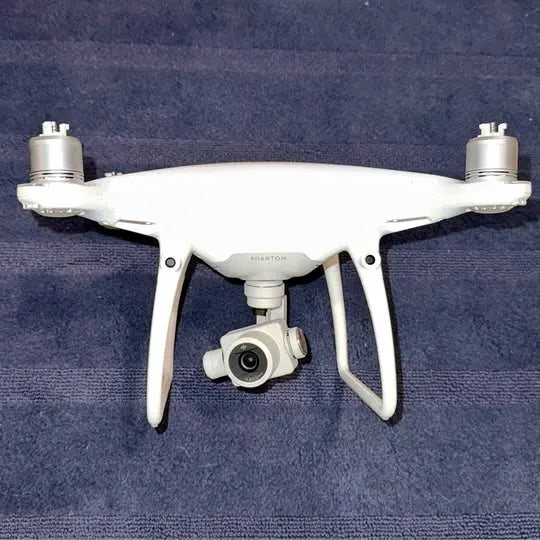 DJI Phantom 4 drone, white quadcopter with front camera and gimbal arms extended