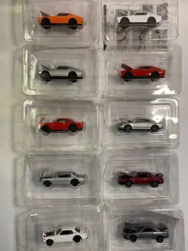 Diecast car models in clear blister tray, including white, red, gray, and orange cars