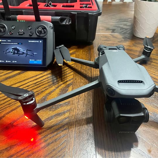 Folding drone with light gray body, propeller guards, and attached gimbal