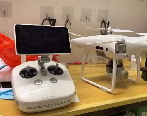 White quadcopter drone with propellers and handheld controller with touchscreen