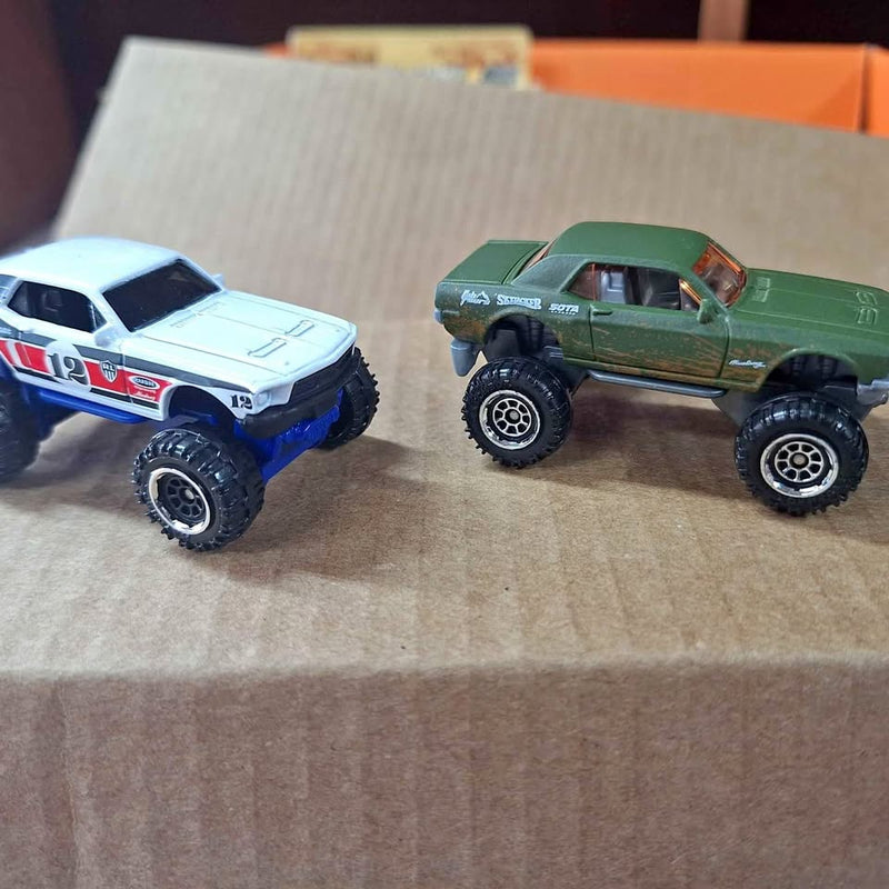 Diecast monster truck pair: white and blue truck plus green off-road truck, both on wheels