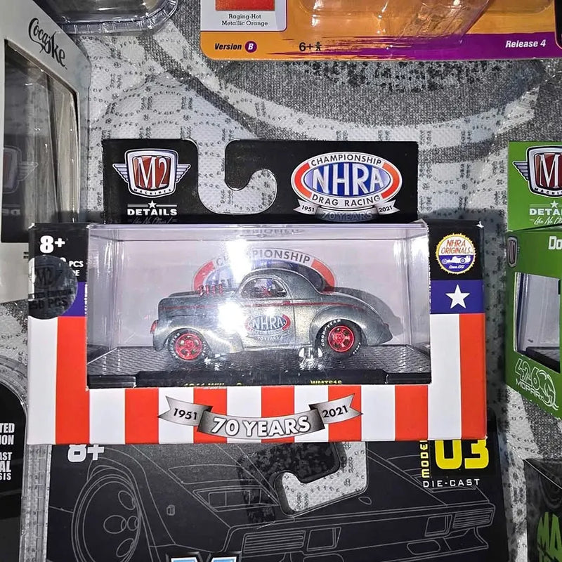 Die-cast NHRA race car toy in blister pack, red-and-silver with '70 Years' badge.