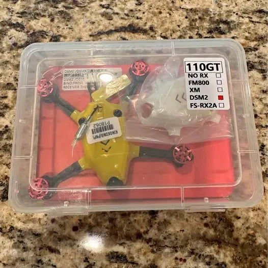 FPV drone parts kit in clear plastic case with yellow controller and red connectors