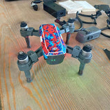 Camouflage quadcopter drone with four arms and propellers, front control screen