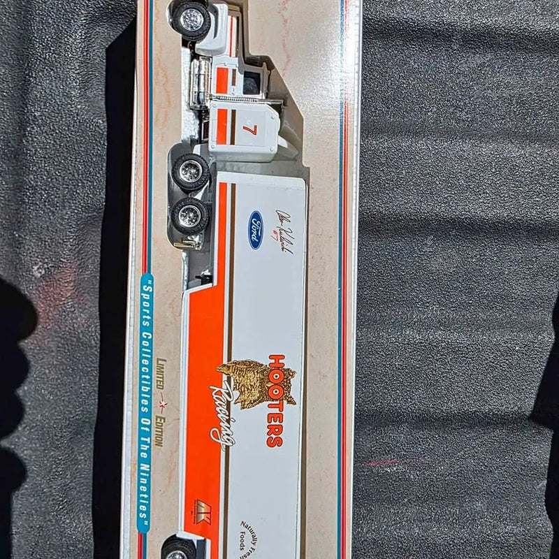 White diecast tractor trailer with orange and blue side graphics, wheels visible