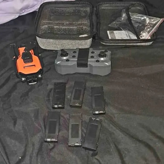 Orange drone with case and multiple batteries, charging accessories laid out