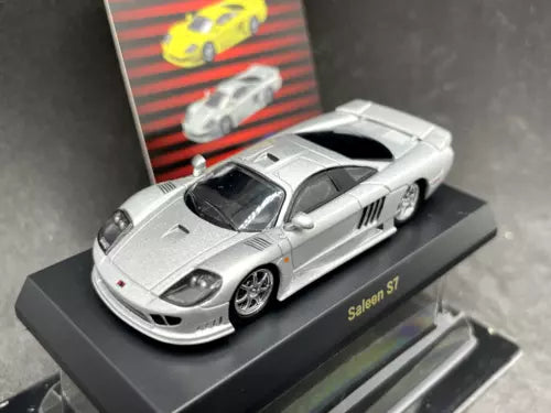 Silver diecast model car with black roof, front three-quarter view on display base