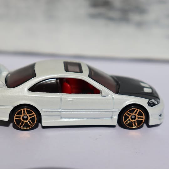 Silver diecast coupe model with black roof, gold-spoke wheels, red interior