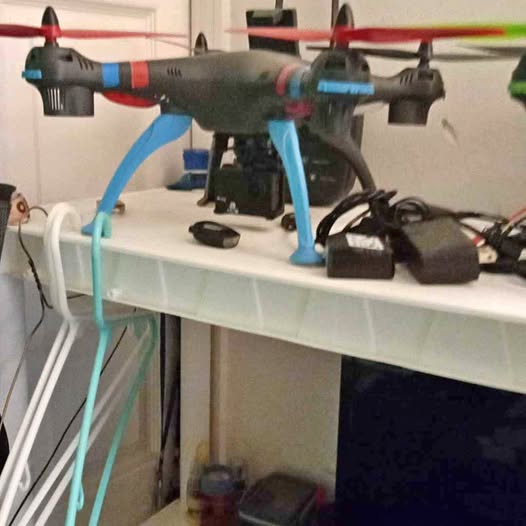 Black quadcopter drone with blue landing legs and red accents