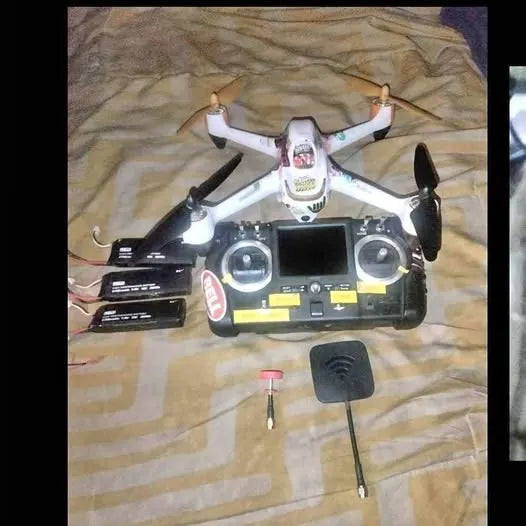 White quadcopter drone with attached camera and black remote controller