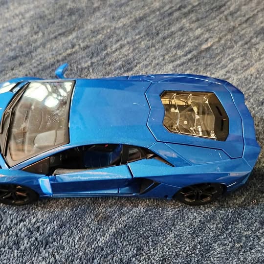 Blue diecast metal sports car with rear spoiler, side view