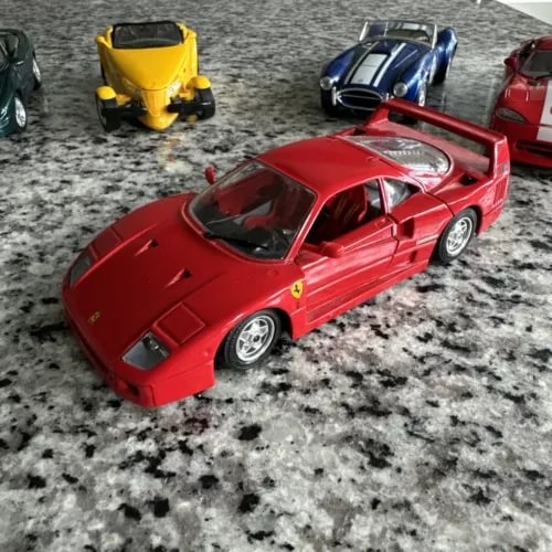 Red diecast sports car model with raised hood and silver wheels