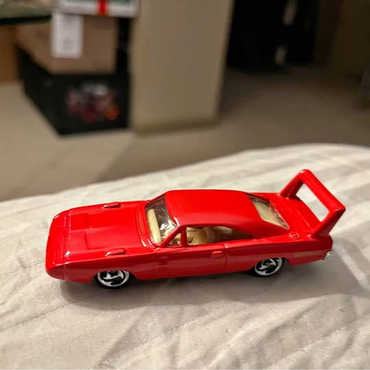 Red diecast sports car with open-spoke wheels and detailed interior, side view