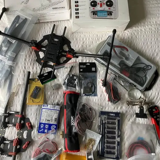 Drone kit with quadcopter frame, antennas, remote controller and accessories in boxes