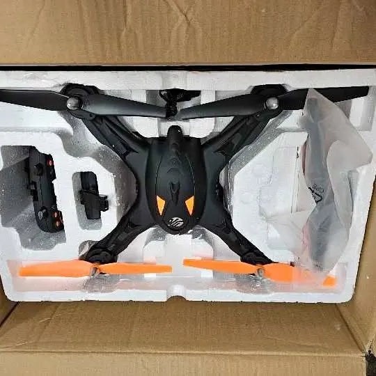 Black quadcopter GPS video drone with orange prop accents in retail box