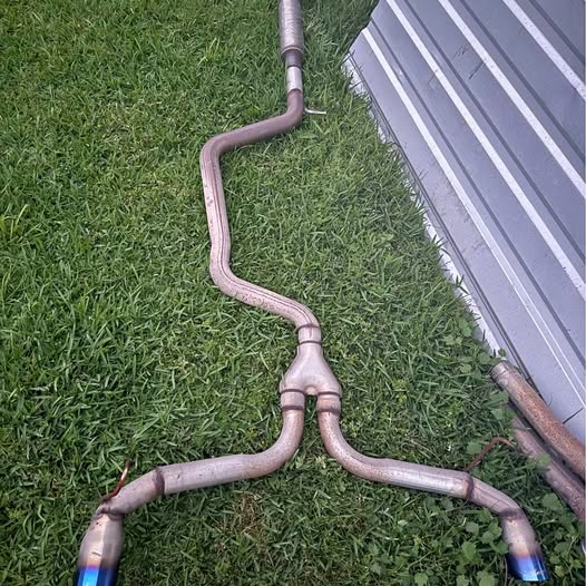 Cat-back exhaust pipes with two curved branches and blue-tinted muffler ends
