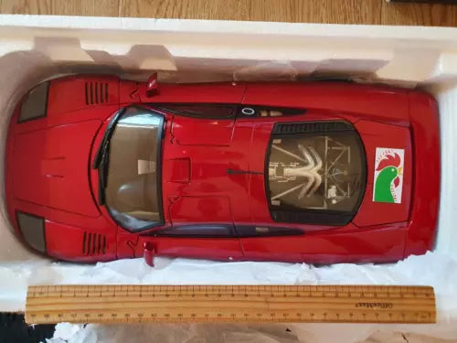 Red 1:12 diecast car model with side windows and front grille details