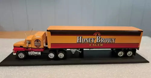 Diecast semi truck and trailer model, honey brown and black, on display base