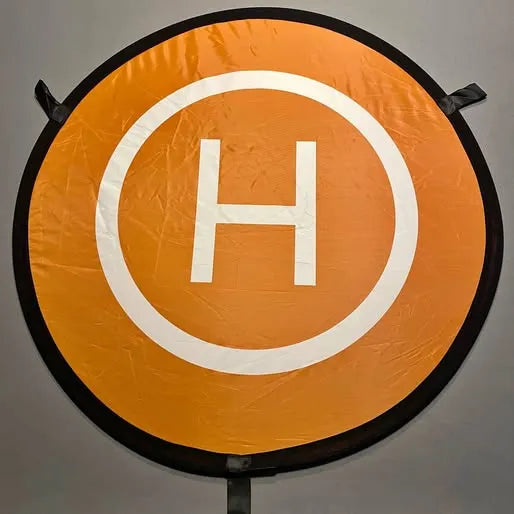 Orange circular drone landing pad with white H symbol and black edge ring