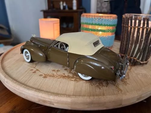Olive green die-cast model convertible car with white tires and side windows