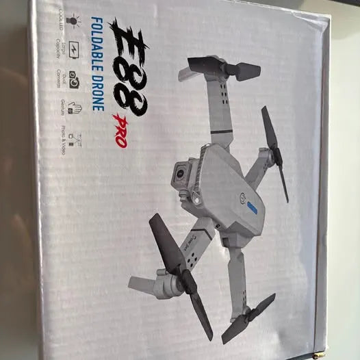 Foldable quadcopter drone with propellers, shown on retail box packaging
