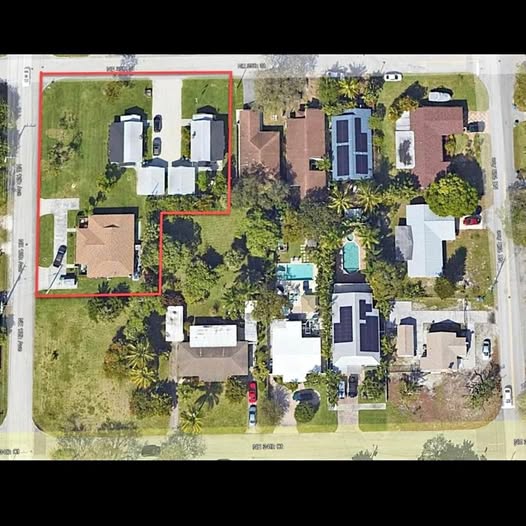 Aerial drone view of residential property with houses, trees, and backyard pool
