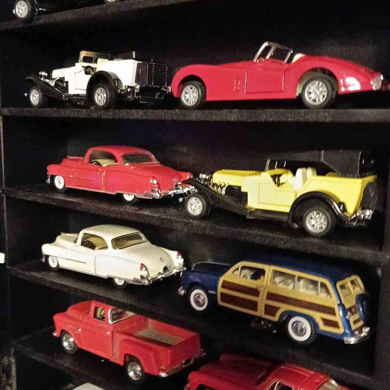 Diecast car collection with red, yellow, white, and blue cars on display shelf