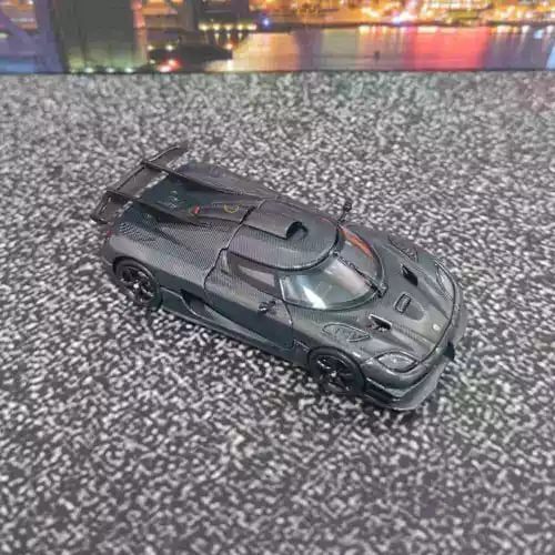 Black 1/64 diecast toy sports car model with detailed carbon-style parts