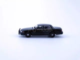 Black diecast police sedan model car, 1:64 scale, side view.