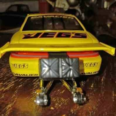 Yellow 1/24 scale pro stock diecast car model with rear wing and open wheels