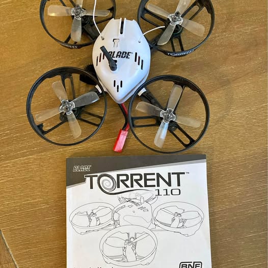 White quadcopter drone with four propellers and Blade Torrent 110 instruction box