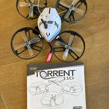 White quadcopter drone with four propellers and Blade Torrent 110 instruction box